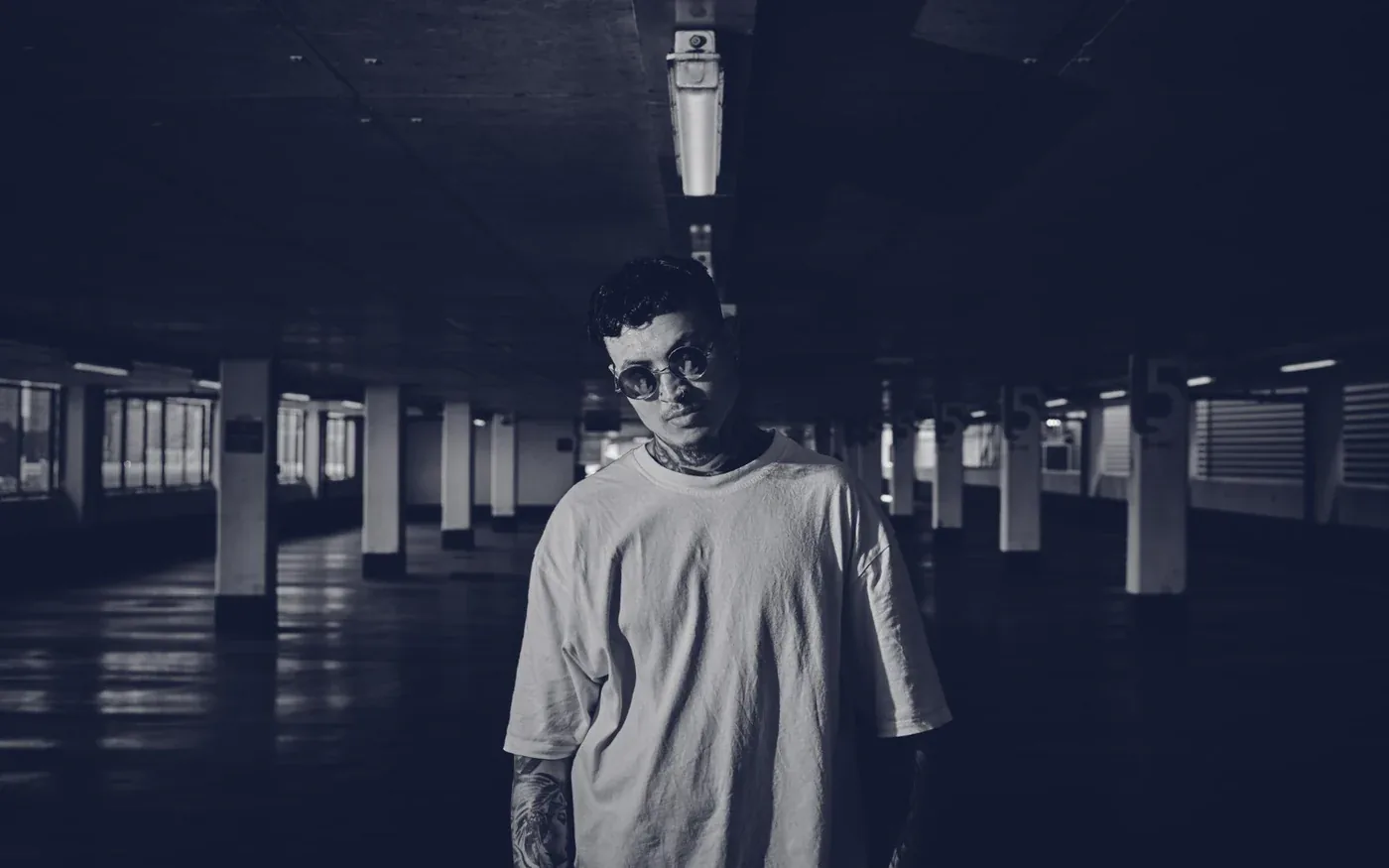 Modelo con lentes y polera oversize ALCORTE en un estacionamiento