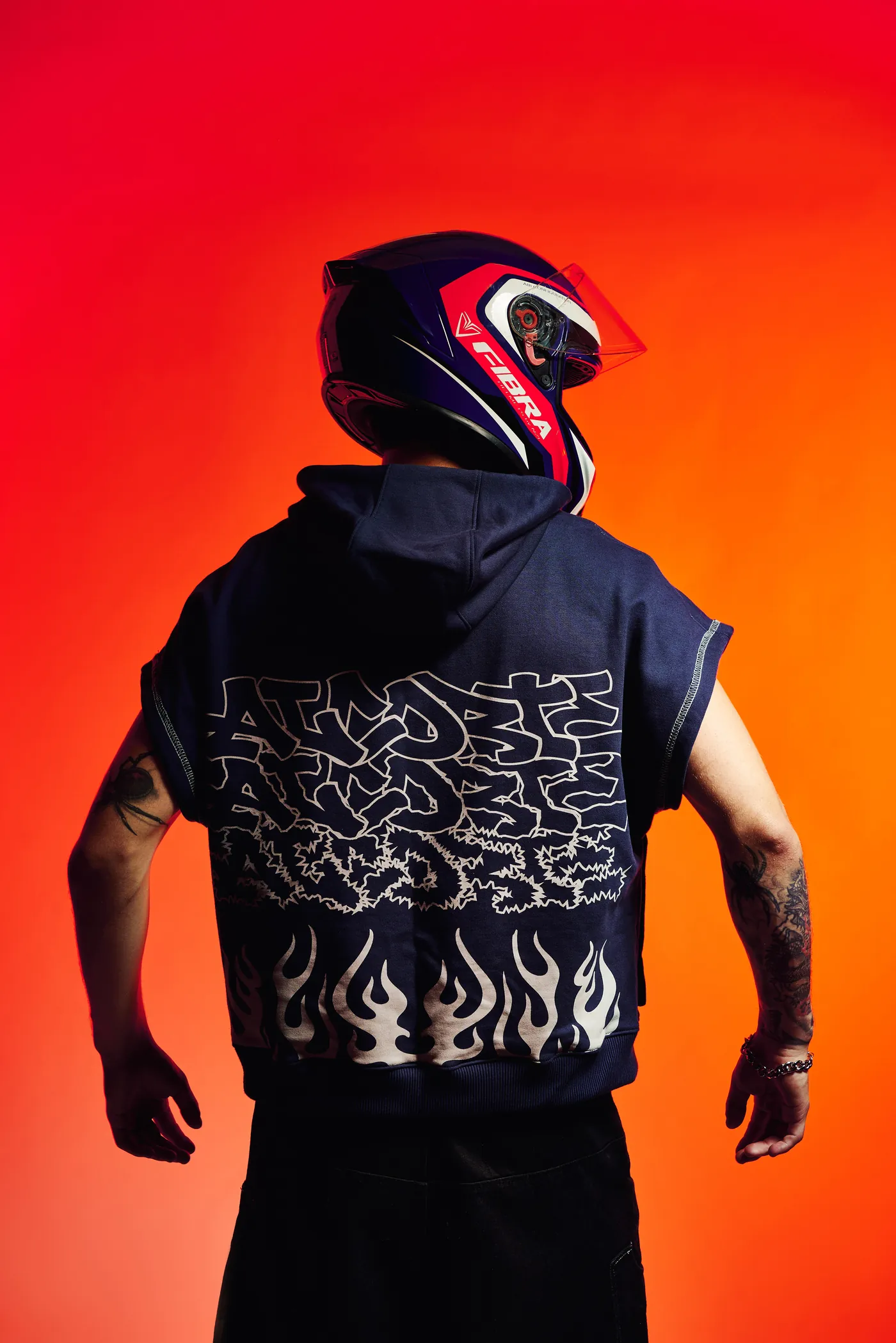 Espalda del Hoodie Flame ALCORTE con casco de carreras, fondo naranja